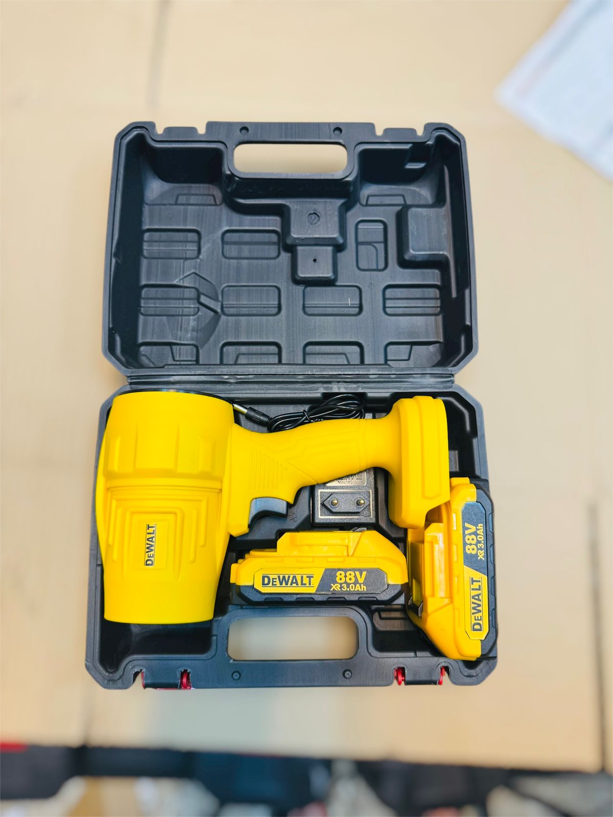 DeWalt power tool with battery in black carrying case on beige surface